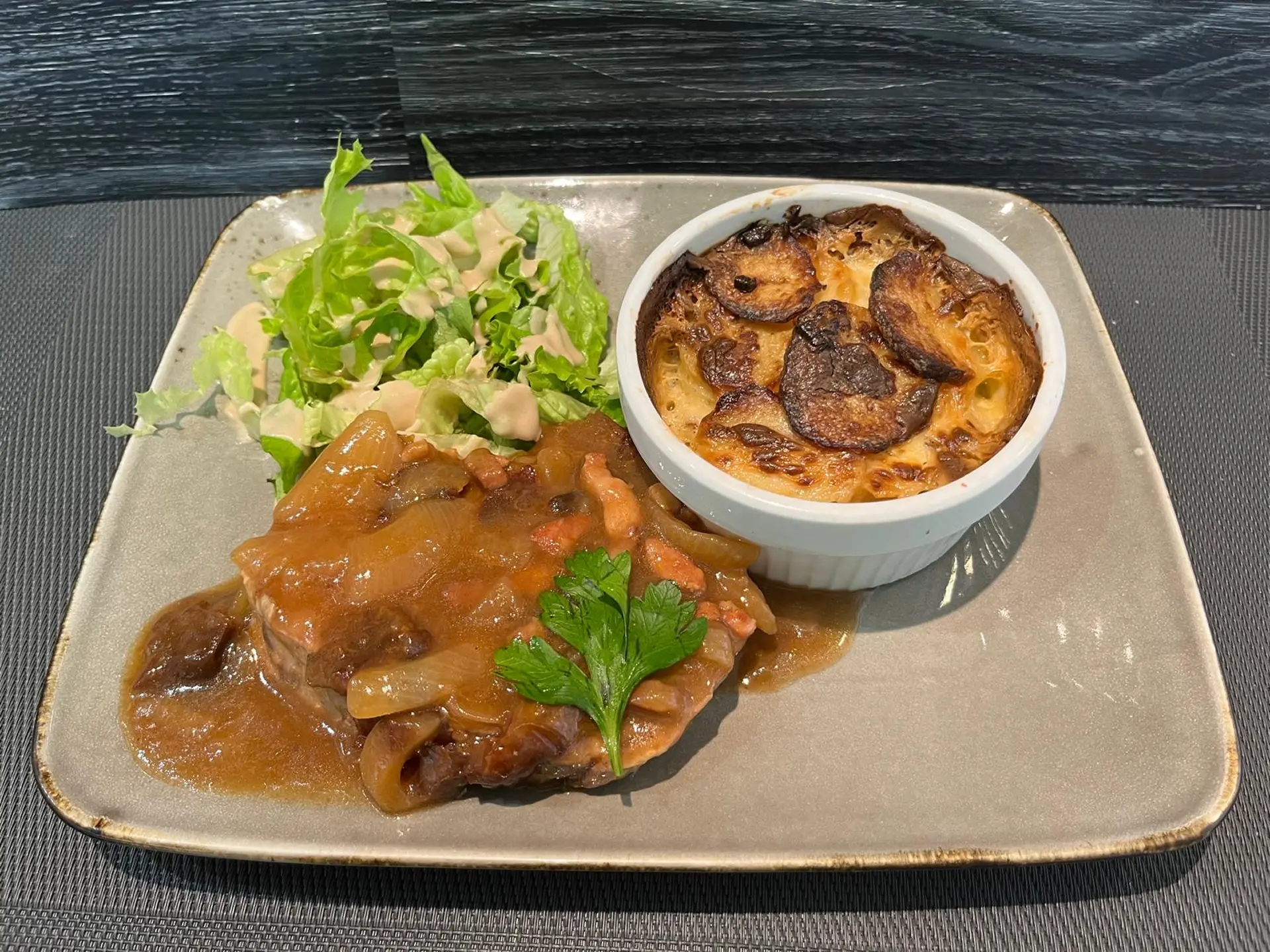 Rôti de cochon (échine) sauce aux pruneaux et lardons, gratin dauphinois et salade verte