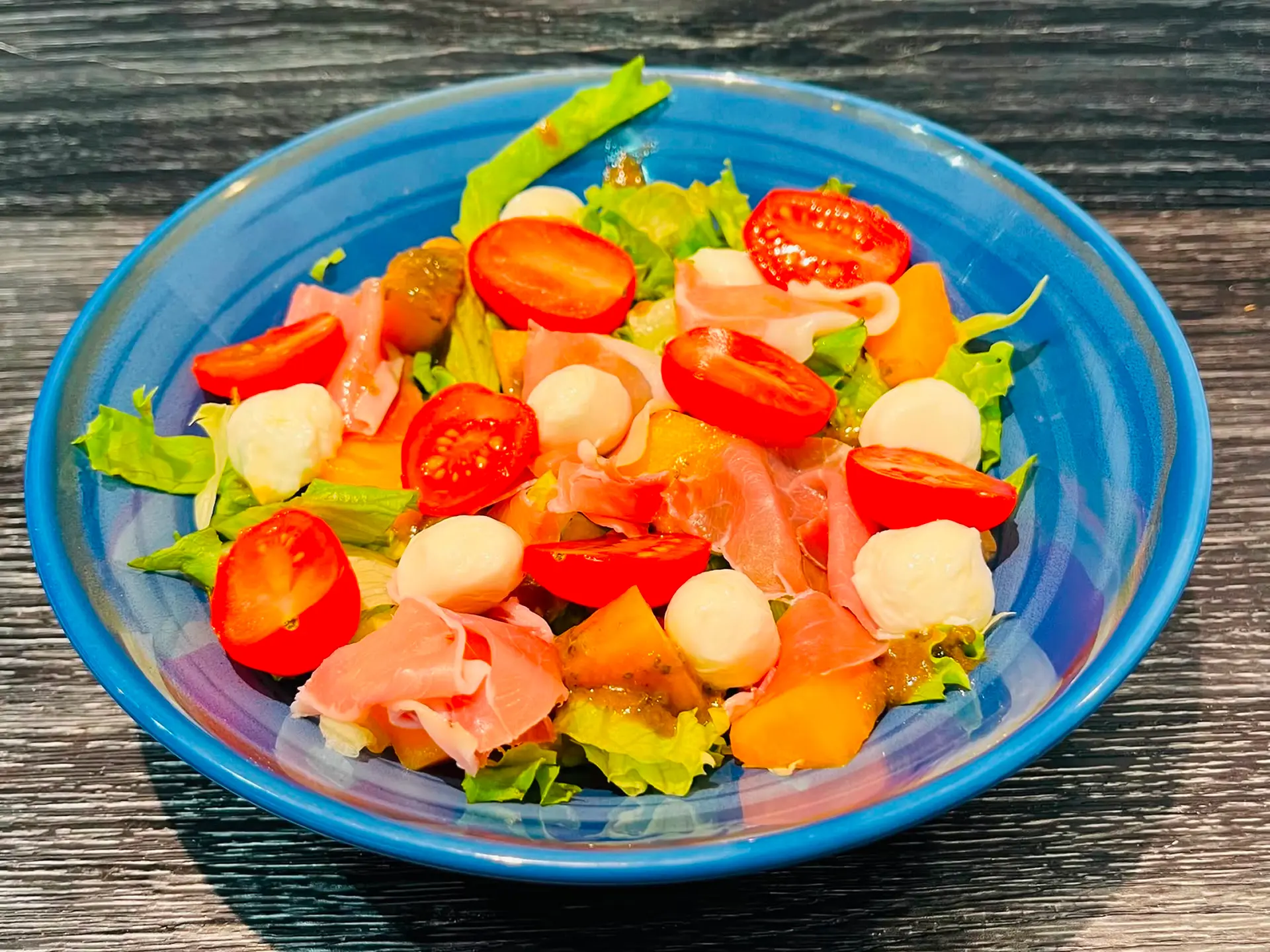 Salade Gourmande au jambon serrano, melon, tomate, billes de mozzarella et vinaigrette au basilic